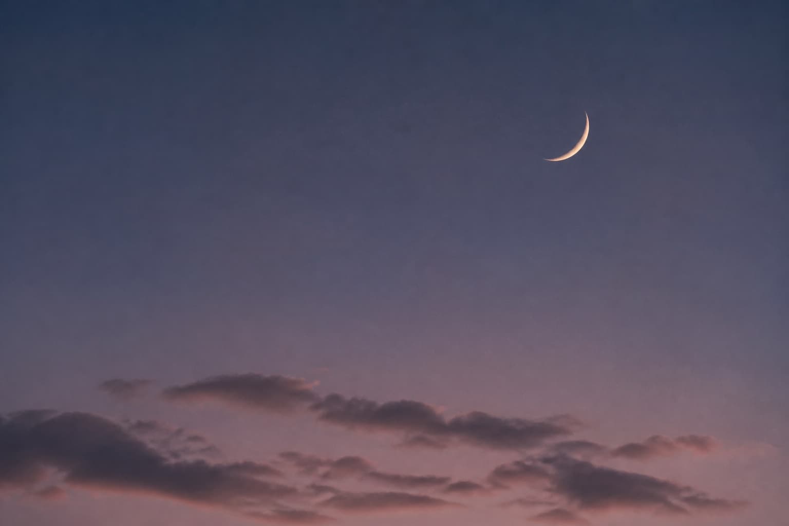 Lua crescente em um céu lilás com nuvens suaves